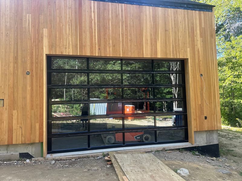 Modern full-view aluminum and glass garage door on contemporary cedar building