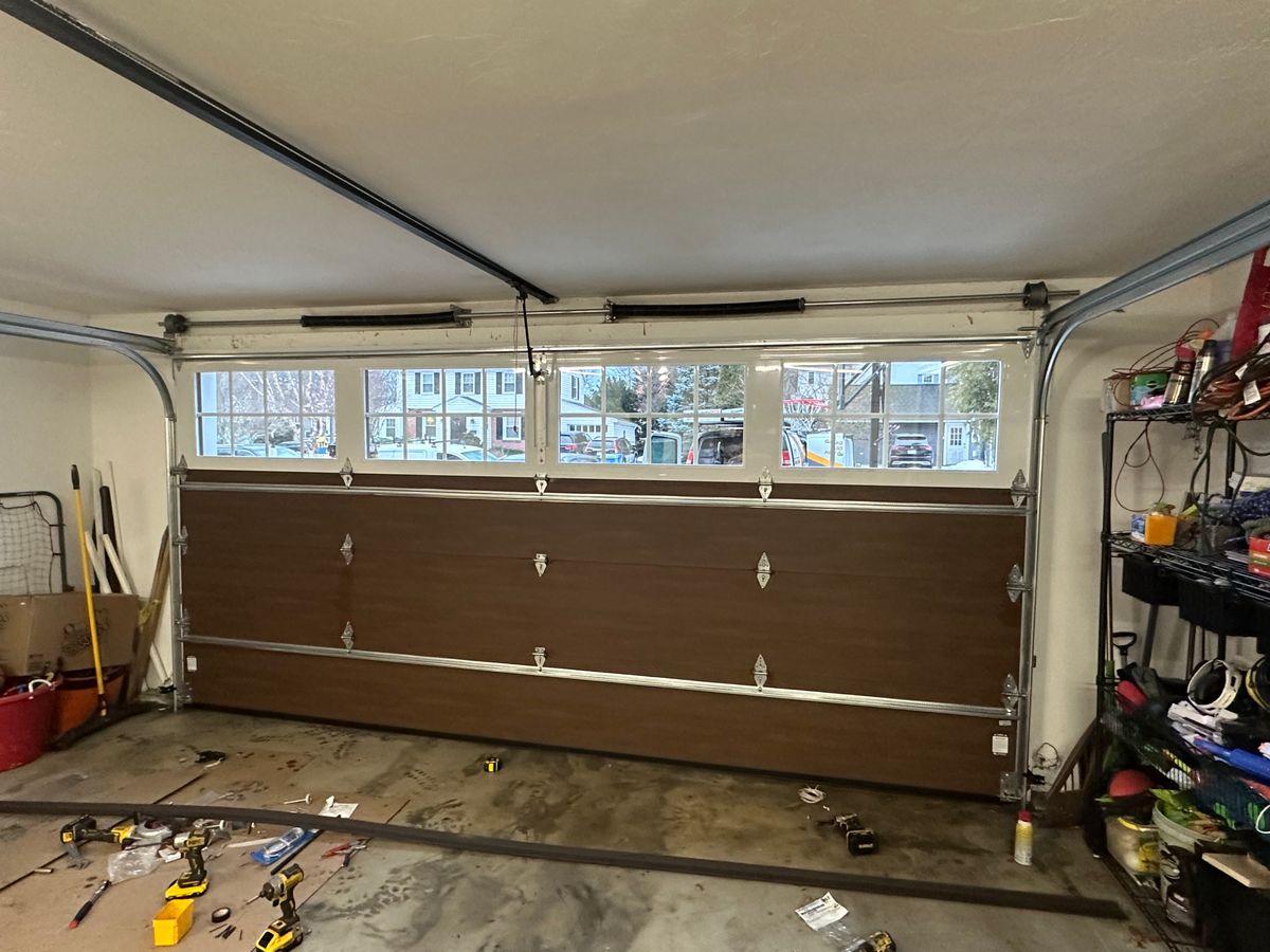 Brown wood-tone garage door interior view with panoramic windows during installation